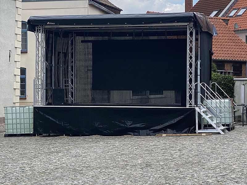 Bühne mieten 6x4 Meter mit schwarzem Dach und Seitengerüst bereit zum Eventaufbau