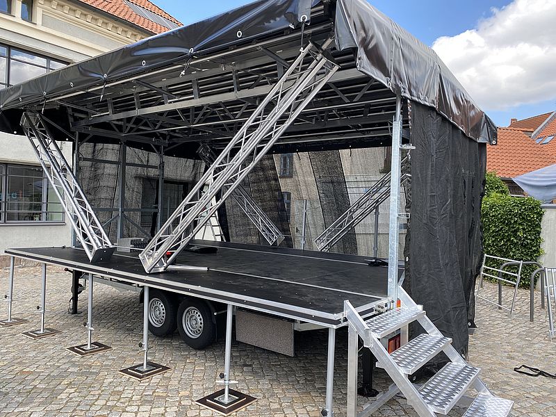 Bühne mieten 6x4 Meter mit schwarzem Überdach und Metallgestell auf gepflastertem Platz