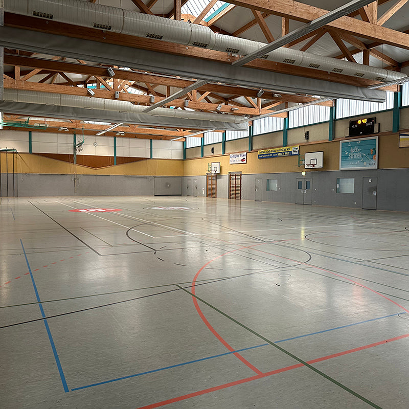 Leere Sporthalle mit sichtbaren Holzbalken und Basketballkörben für Hallendekoration mieten
