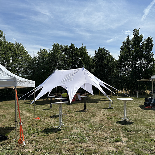 Weißes Sternenzelt auf Wiese bei Sonnenschein mit Stehtischen zum Sternenzelt mieten Wismar